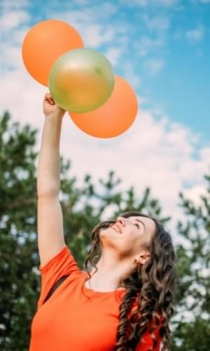smiling woman holding balloons